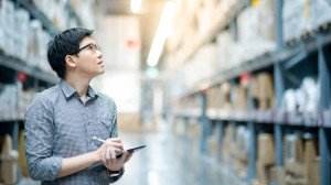 Asian man doing stocktaking by using tablet in warehouse